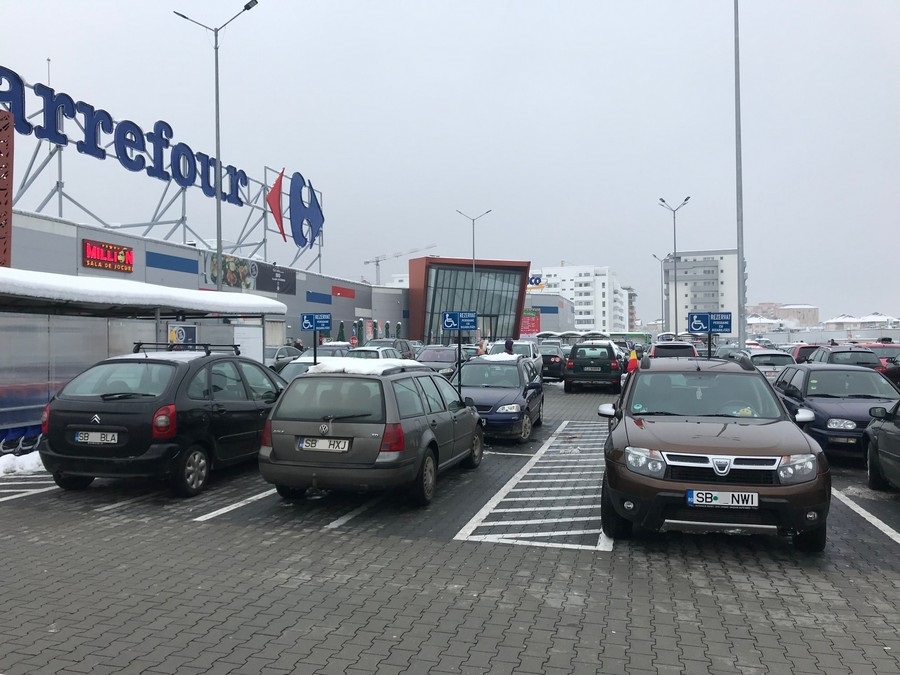 În vreme ce ignoră problema parcărilor ilegale pe locurile celor cu dizabilităţi, Shopping City Sibiu măcar şi-a marcat parcările în culori.
